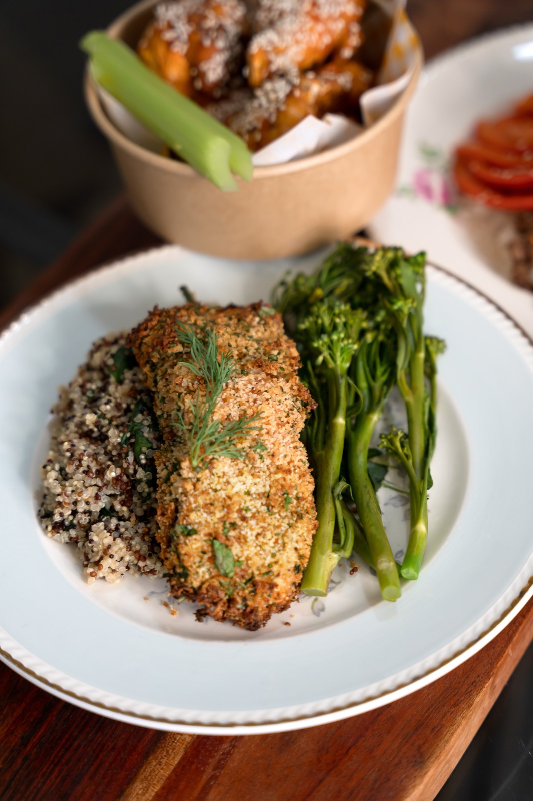 Herb-crumbed chicken on quinoa with broccolini and a bowl of sweet potato wedges