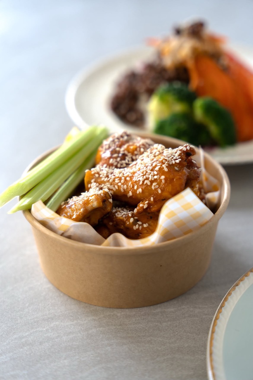 Sticky sesame chicken in a takeaway tub with celery, fresh from the kitchen