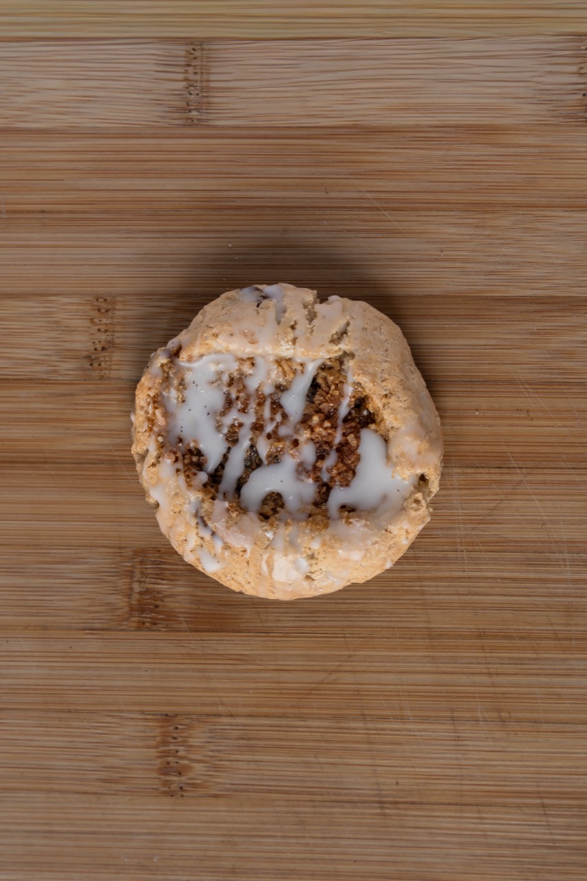 Iced cookie with a sweet drizzle glaze on a timber board