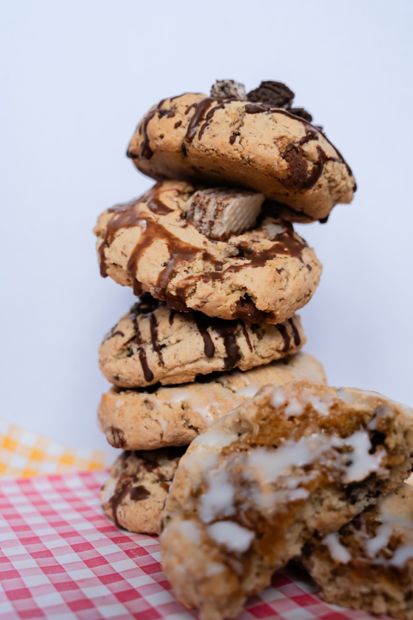A tall stack of freshly baked cookies with chocolate drizzle on gingham