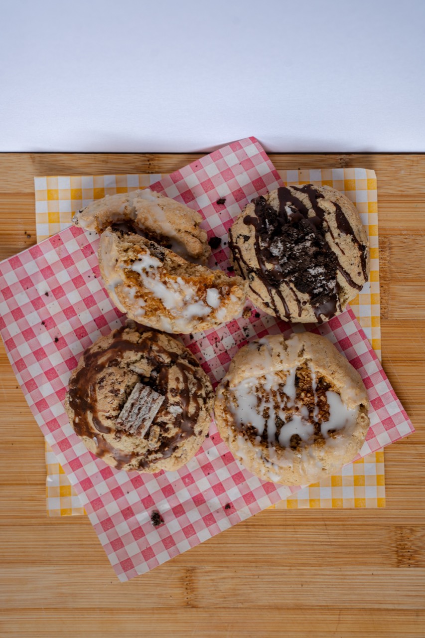 Four assorted iced and drizzled cookies laid out on gingham, ready to box