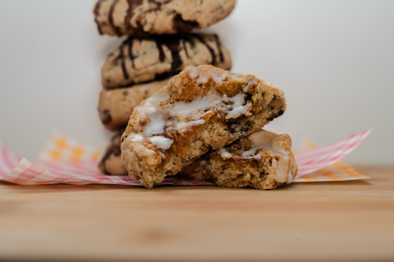 Freshly baked cookies with chocolate drizzle, one broken open to show a gooey centre