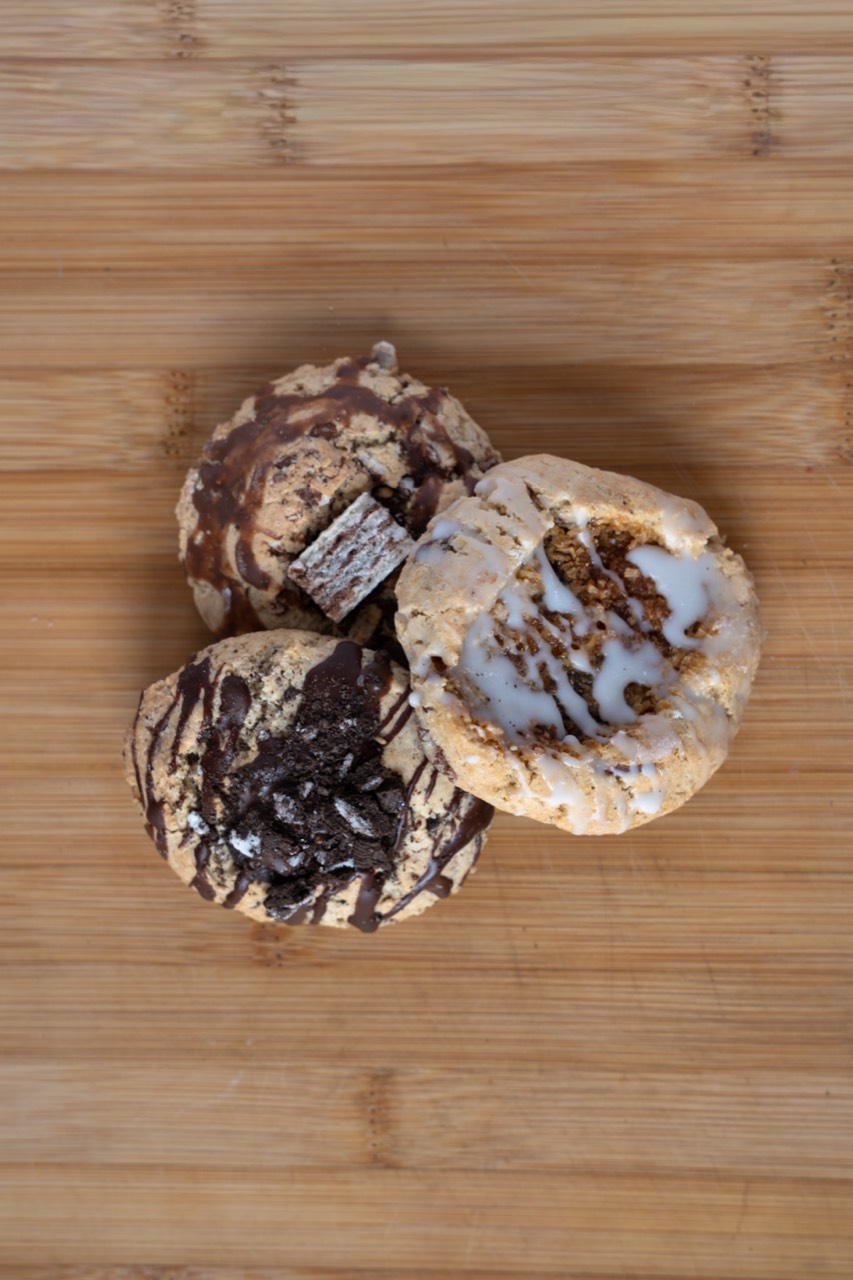 Three assorted freshly baked cookies grouped on a timber board